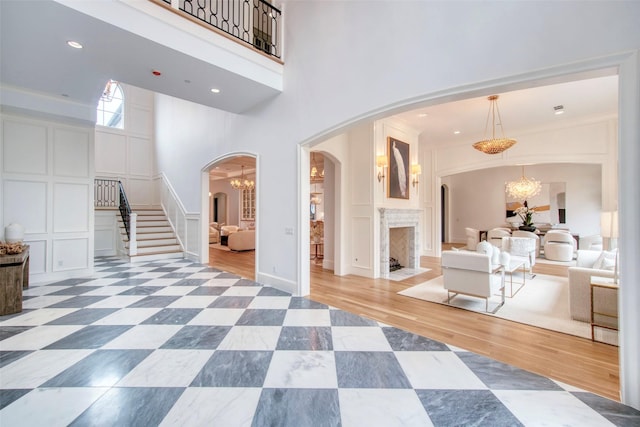 entryway featuring a towering ceiling, an inviting chandelier, arched walkways, and a decorative wall