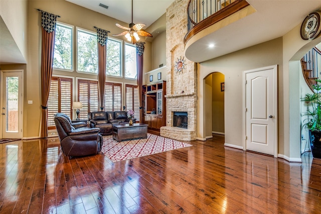 living room with hardwood / wood-style flooring, plenty of natural light, a high ceiling, and a fireplace