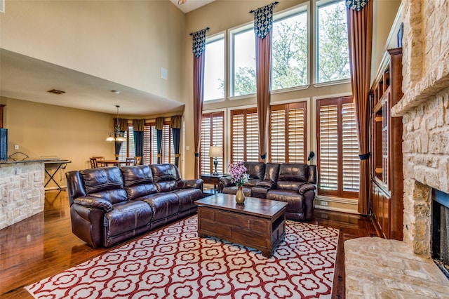 living room with a towering ceiling, wood-type flooring, a fireplace, and plenty of natural light