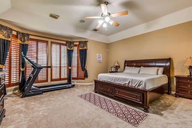 carpeted bedroom featuring a raised ceiling and ceiling fan