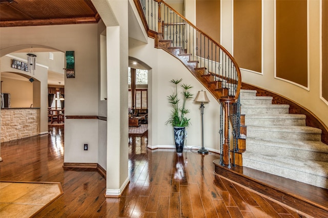 stairs featuring a towering ceiling and wood-type flooring