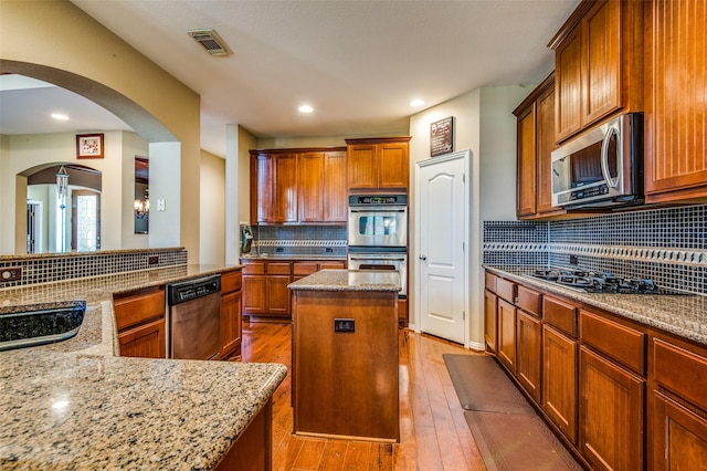 kitchen featuring light stone counters, appliances with stainless steel finishes, light hardwood / wood-style floors, and a kitchen island