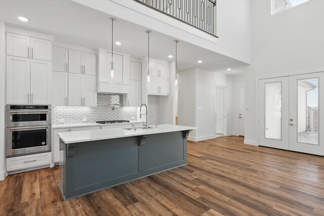 kitchen with an island with sink, white cabinetry, light countertops, and a sink