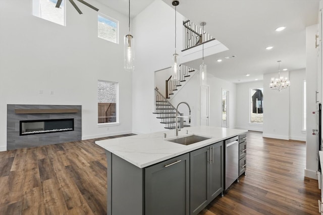 kitchen with open floor plan, a sink, a kitchen island with sink, and gray cabinetry