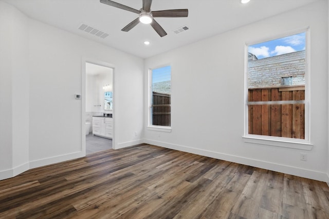 spare room featuring dark wood-style flooring, visible vents, and baseboards