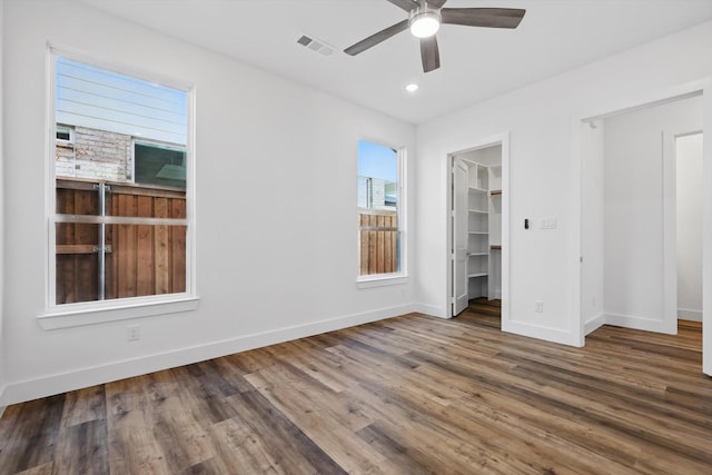 unfurnished bedroom featuring recessed lighting, visible vents, a spacious closet, wood finished floors, and baseboards