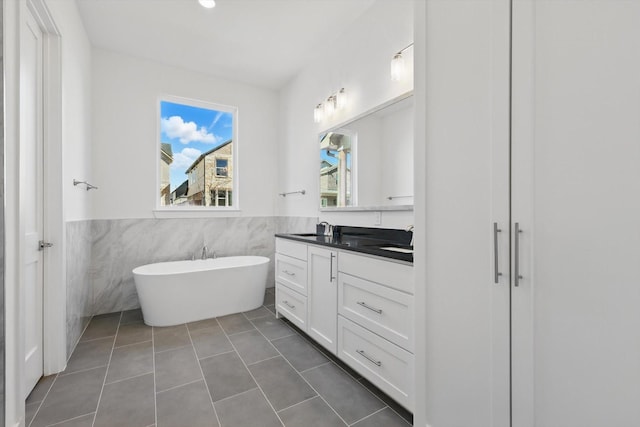 full bathroom with tile patterned floors, wainscoting, a freestanding bath, and vanity