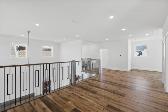 corridor featuring baseboards, wood finished floors, and recessed lighting