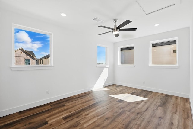 empty room featuring dark wood-style flooring, recessed lighting, visible vents, and baseboards