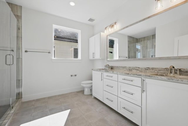 bathroom with a shower stall, double vanity, a sink, and baseboards