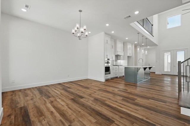 unfurnished living room with dark wood-style floors, a wealth of natural light, visible vents, and baseboards