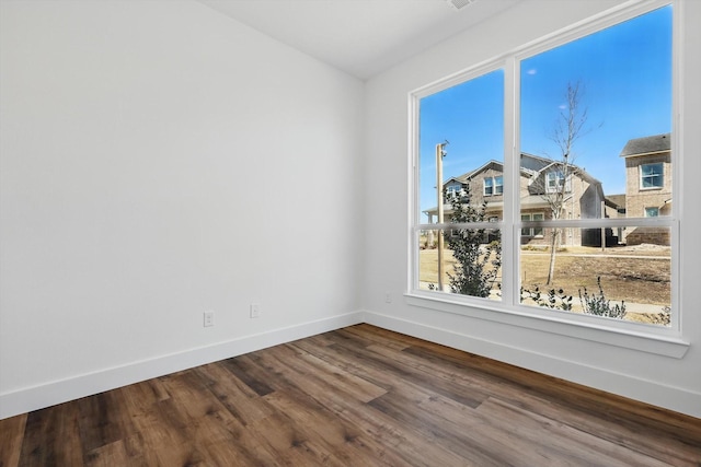 spare room featuring baseboards and wood finished floors