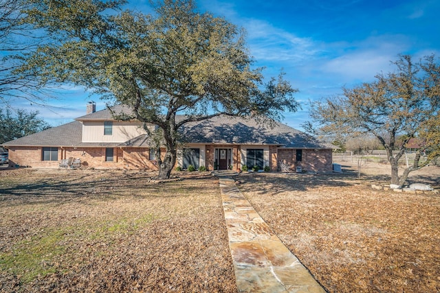 view of front of property with a front lawn, a chimney, and brick siding