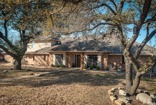 view of front of home with brick siding, a shingled roof, and a front lawn