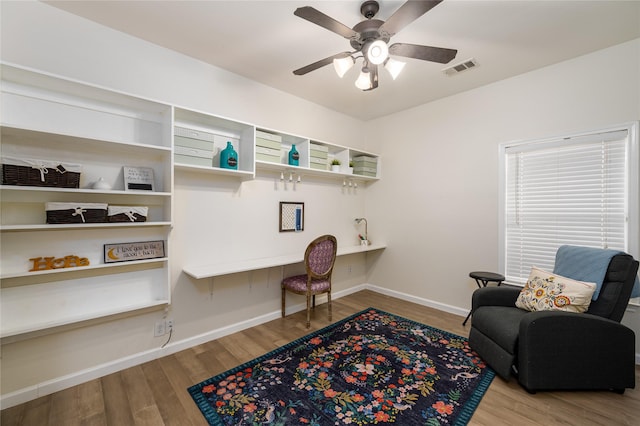 office space featuring ceiling fan, built in desk, and light hardwood / wood-style flooring