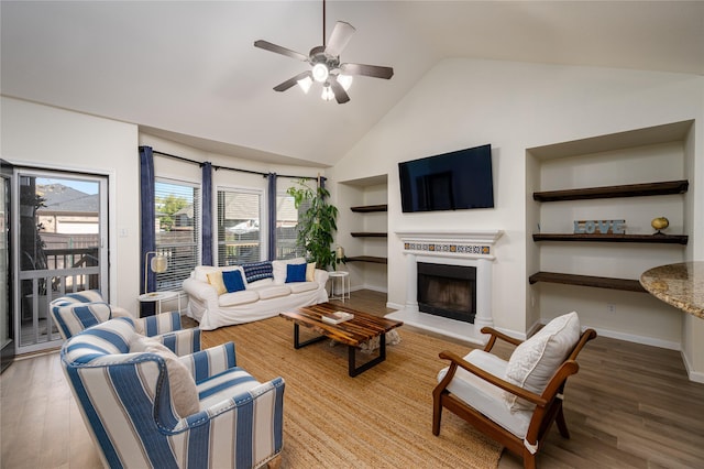 living room featuring hardwood / wood-style floors, built in shelves, high vaulted ceiling, and ceiling fan