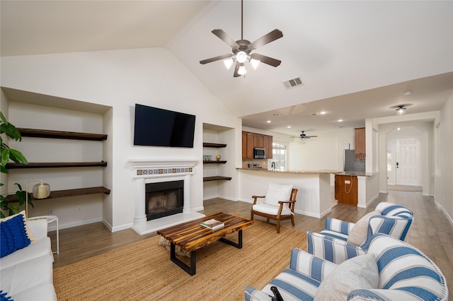 living room featuring ceiling fan, high vaulted ceiling, and light hardwood / wood-style floors