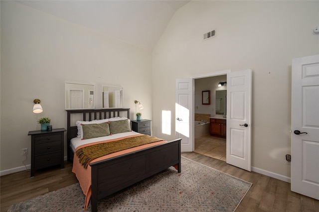 bedroom with connected bathroom, hardwood / wood-style floors, and high vaulted ceiling