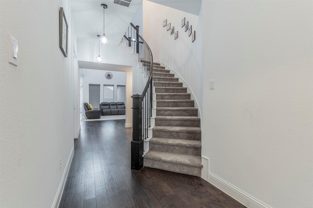 foyer with a towering ceiling and dark wood-type flooring