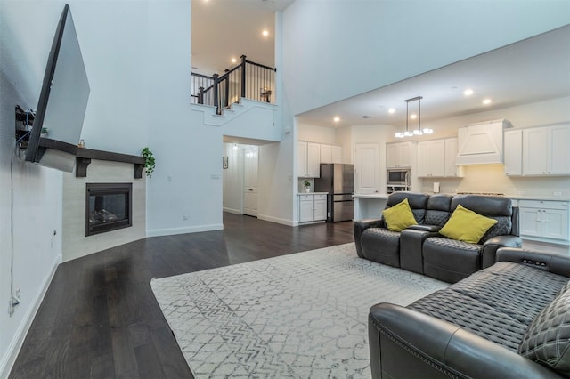 living room featuring a towering ceiling, a fireplace, and dark hardwood / wood-style flooring