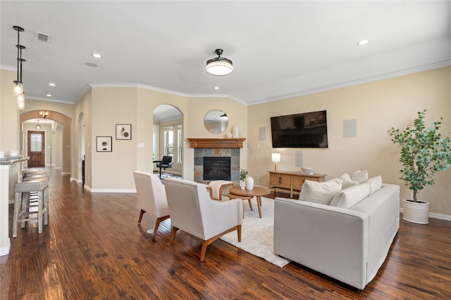 living room with a tile fireplace, dark wood-type flooring, and ornamental molding