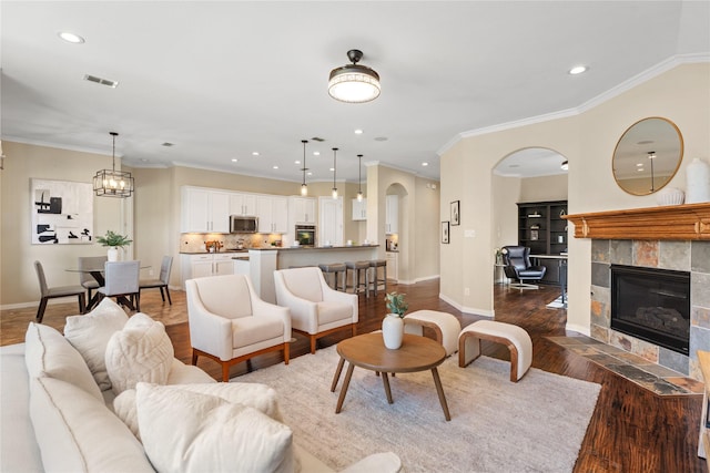 living room featuring crown molding, dark hardwood / wood-style flooring, and a tile fireplace