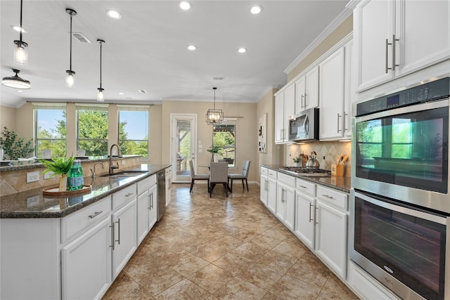 kitchen featuring white cabinetry, stainless steel appliances, decorative light fixtures, and sink