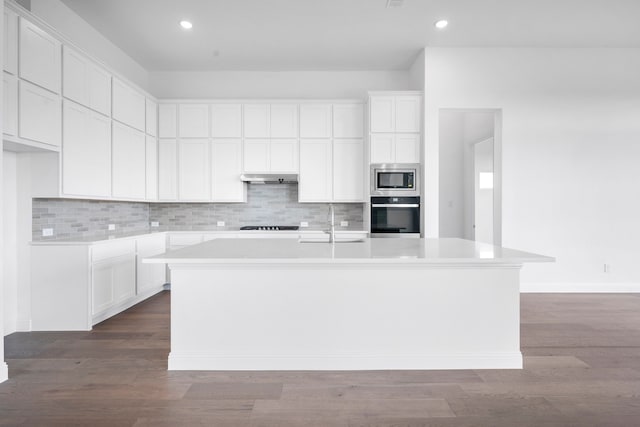 kitchen featuring backsplash, a center island with sink, stainless steel appliances, and a sink