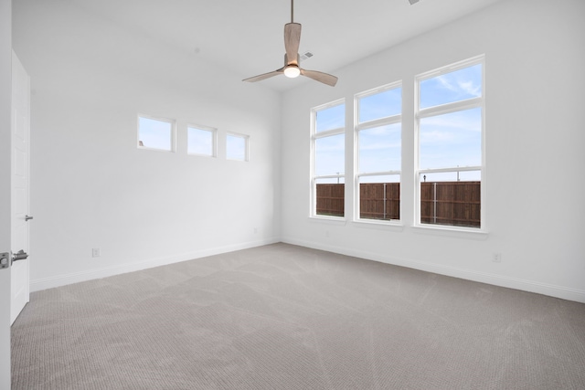 carpeted spare room featuring ceiling fan and baseboards