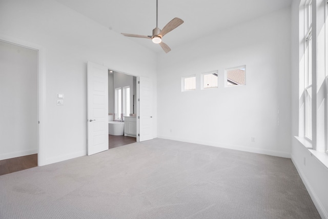 unfurnished bedroom featuring ceiling fan, ensuite bath, carpet flooring, and baseboards