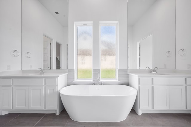 full bath with a freestanding bath, tile patterned flooring, and a sink