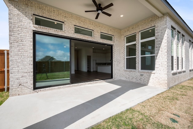 property entrance with ceiling fan, brick siding, and a patio area