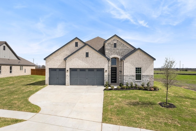 french country style house featuring a garage, concrete driveway, stone siding, a front yard, and brick siding