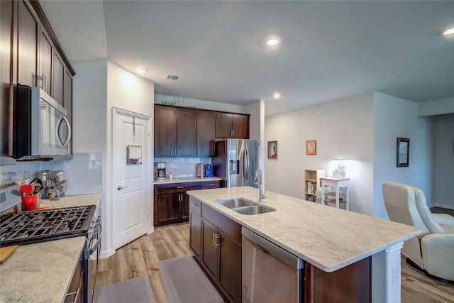 kitchen with sink, a kitchen island with sink, dark brown cabinetry, light hardwood / wood-style floors, and stainless steel appliances