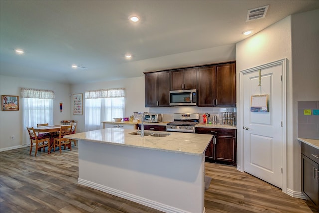 kitchen with sink, dark brown cabinets, an island with sink, and appliances with stainless steel finishes