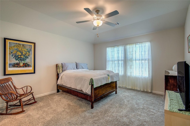 bedroom featuring a raised ceiling, light carpet, and ceiling fan