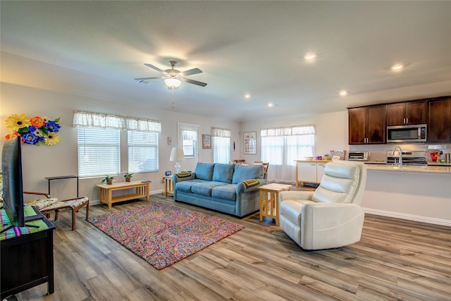 living room featuring sink, light hardwood / wood-style flooring, and ceiling fan