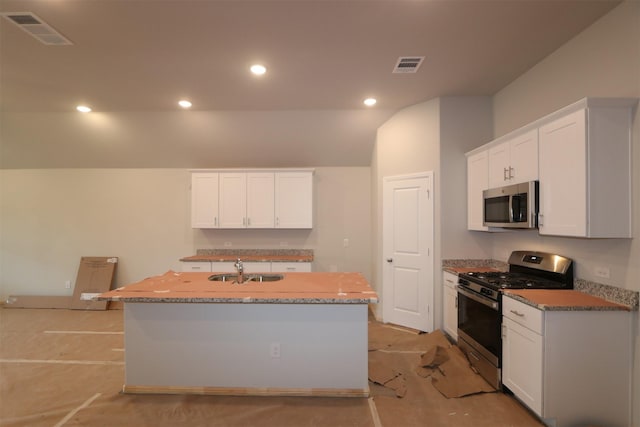 kitchen featuring white cabinetry, visible vents, appliances with stainless steel finishes, and a center island with sink