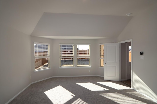 unfurnished room featuring lofted ceiling, dark colored carpet, and baseboards