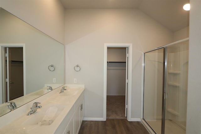 bathroom featuring a shower stall, a spacious closet, vaulted ceiling, and a sink