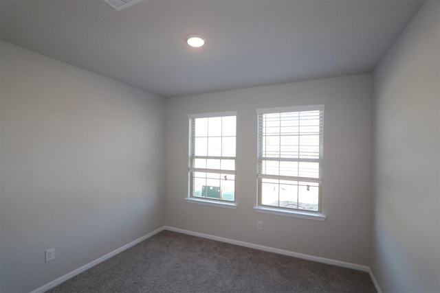 spare room featuring dark carpet and baseboards