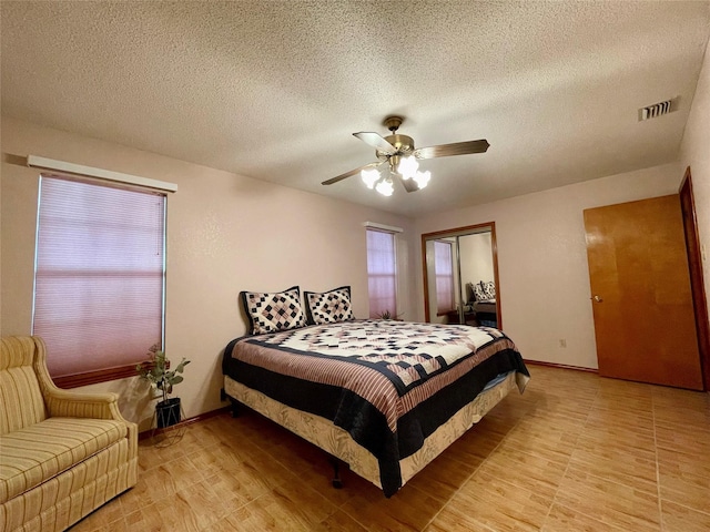 bedroom with a textured ceiling, ceiling fan, and light wood-type flooring