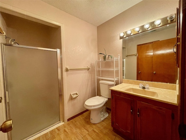 bathroom with vanity, toilet, a textured ceiling, and a shower with shower door