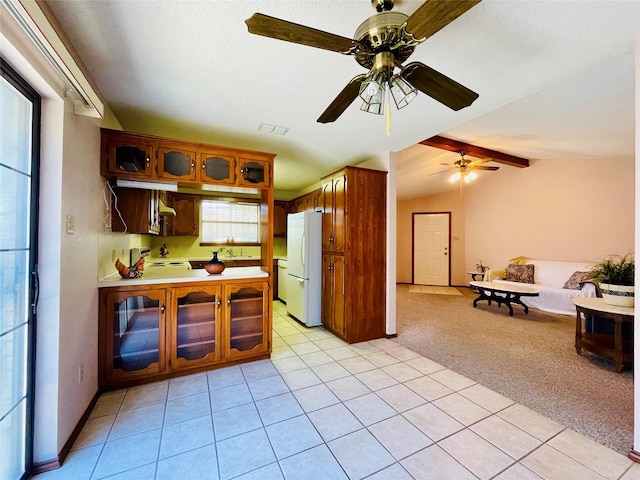 kitchen featuring light carpet, lofted ceiling with beams, stove, and white refrigerator