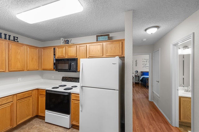 kitchen with sink, a textured ceiling, white appliances, and light hardwood / wood-style floors