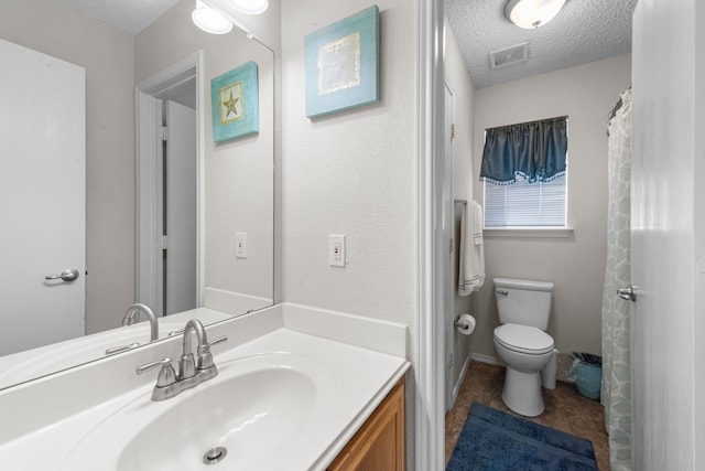 bathroom featuring vanity, toilet, tile patterned flooring, and a textured ceiling