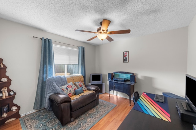 living area with a textured ceiling, wood-type flooring, and ceiling fan