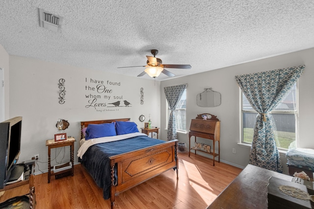 bedroom with hardwood / wood-style floors, a textured ceiling, and ceiling fan