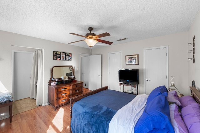 bedroom with a textured ceiling, ceiling fan, and light hardwood / wood-style flooring