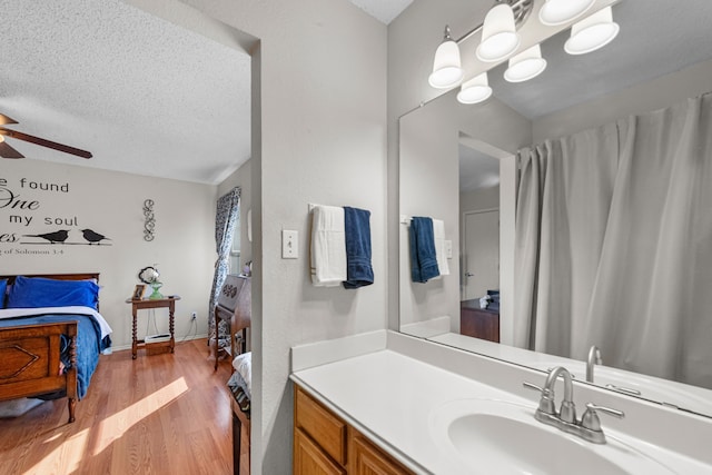 bathroom featuring vanity, ceiling fan, wood-type flooring, and a textured ceiling